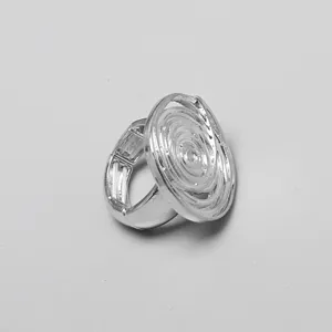 Vista detallada de un anillo elástico de metal plateado con un diseño de flor en espiral ovalada