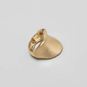 Primer plano de anillo elástico dorado con forma ondulada y textura de metal cepillado.