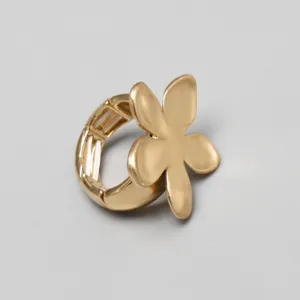 Detalle macro de un anillo con forma de flor dorada y banda elástica extensible.