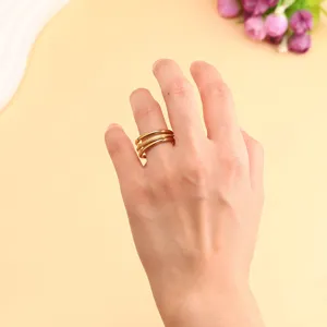 Close-up detail of a minimalist three-layered stacked golden titanium steel ring on hand