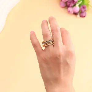 Close-up detail of three-layer stacked titanium steel rings in gold and silver finish