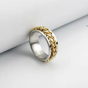 Close-up of a silver stainless steel spinner ring with a rotating gold chain link.