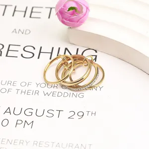 Macro view of three-layer stacked gold titanium steel rings featuring delicate crystal accents