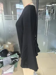 Side view of black long sleeve top with flared bell sleeves and waist tie detail