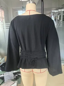 Back view detail of a black boat neck top featuring flare sleeves and a tie waist