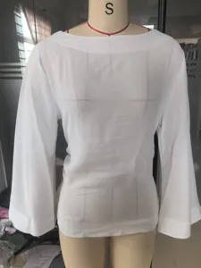 Detailed view of a white boat neck top with long flare sleeves displayed on a mannequin