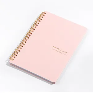 Close-up of elegant pink non-dated weekly planner notebook with gold spiral binding