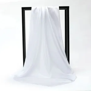 Elegant white silky square scarf draped on black frame showing soft texture and folds.