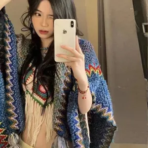 Detail view of colorful ethnic style knit shawl with tassels worn by model