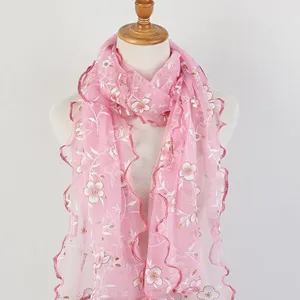 Detail view of a pink floral printed scarf with ruffled wood ear edges on a mannequin.