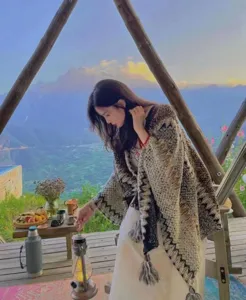 Warm ethnic style knit shawl with tassels worn in a scenic outdoor camping setting