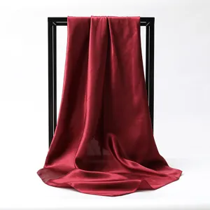 Close-up of burgundy satin square scarf draped over a black display frame