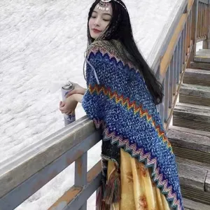 Ethnic style knitted shawl wrap worn by a woman in a snowy winter mountain landscape