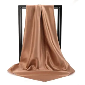 Detail view of premium champagne satin silk square scarf with elegant draped fabric texture