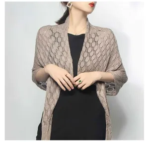Detailed view of a lightweight tan knitted shawl featuring a hollow-out honeycomb pattern.