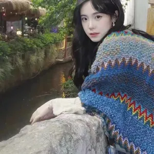 Ethnic style knitted shawl with vibrant zig-zag pattern worn by model in outdoor setting
