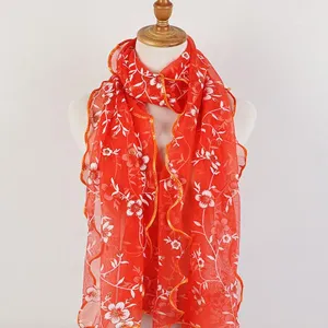Close-up of bright orange long scarf with white floral leaf print and ruffled wood ear edges