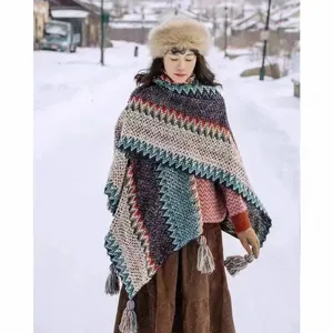 Asian woman wearing a thick ethnic knit shawl with tassels in a snowy village landscape