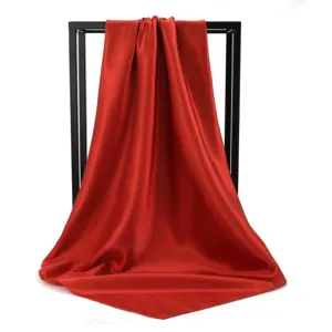 Close-up detail of smooth red silk square scarf with elegant sheen and soft texture