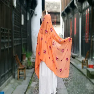 Back view of orange cotton linen shawl with delicate floral embroidery in an old alley