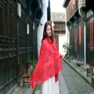 Elegantly styled woman wearing a red embroidered ethnic cotton linen shawl in a traditional alley