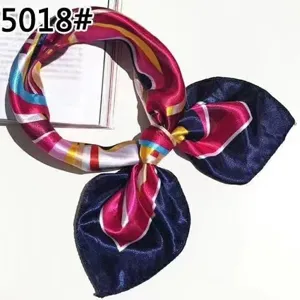 Close-up of a navy blue and magenta patterned silk scarf tied in a professional bow knot.