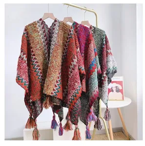 Detailed view of colorful bohemian knit ponchos with decorative tassels hanging on a rack