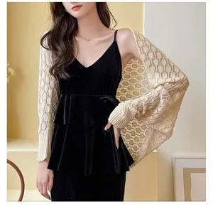 Close-up view of a cream honeycomb hollow-out knitted shrug paired with a black velvet dress