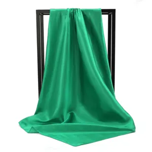 Close-up of vibrant emerald green silk scarf draped elegantly over a minimal black frame