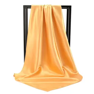 Detail showing the elegant drape and silk luster of a solid gold satin square scarf.