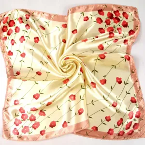 Detail of a cream silk square scarf with red flowers and pink stitched edges.