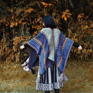 Bohemian ethnic style thick knitted poncho shawl for women in autumn forest.