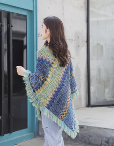 Back view of bohemian knitted poncho featuring colorful zigzag patterns and fringe trim.