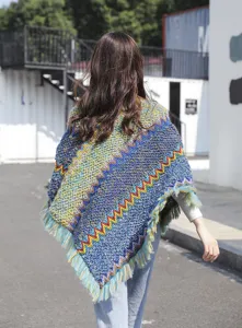 Back view of bohemian knitted poncho with colorful zigzag patterns and fringe details