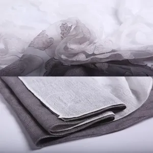 Macro detail of gray and white lace floral scarf with tie-dye pattern and hollowed cut