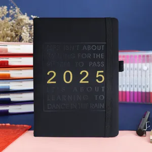 Primer plano de agenda 2025 en inglés con frase motivadora en relieve y tapa negra