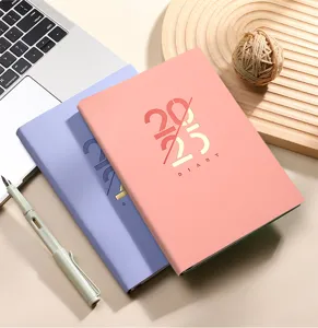 Detalle de las agendas 2025 en rosa y lavanda en un escritorio de trabajo organizado.