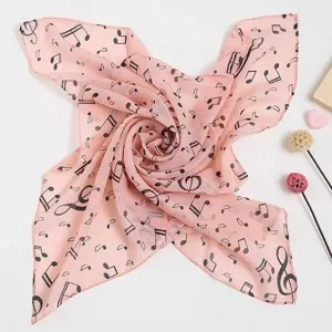 Nahaufnahme eines rosa Seidenschals mit schwarzem Notendruck und weicher Textur.