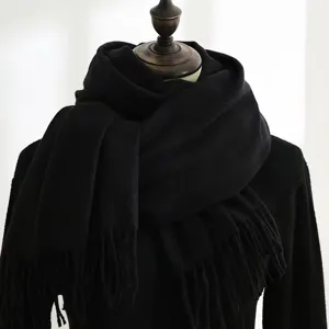 Macro view of the thick black scarf with soft fringe detail and woven wool texture