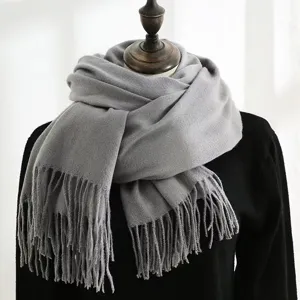 Detailed view of the thick gray winter scarf with soft tassels on a mannequin