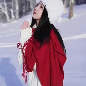 Elegant red winter scarf with tassels worn by a model in a snowy outdoor landscape scenery