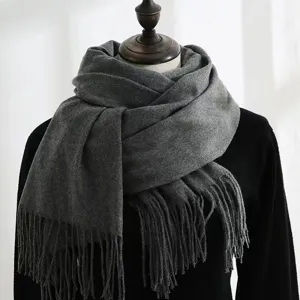 Close-up detail of a dark grey thick winter warm scarf with elegant fringed edges on a mannequin