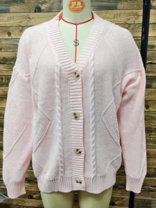 Close-up detail of pink V-neck knitted cardigan showing jacquard texture and buttons