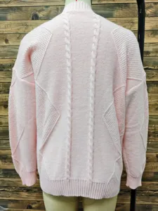 Detail view of a pink jacquard knit sweater with cable stitch and ribbed hem details.