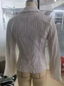 Detailed back view of a white long-sleeved shirt featuring elegant vertical pleat texture