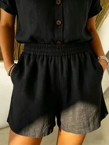 Detailed macro view of black cotton linen shorts with elastic waist and wood buttons