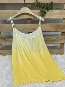 Detail view of a yellow ombre pleated camisole hanging on a wooden pallet backdrop