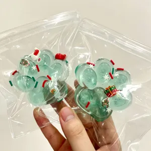 Close-up of festive green cat paw squishy toys with Christmas decor in clear packaging