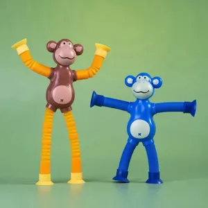Close-up of two colorful monkey pop tube toys with suction cup limbs on green background