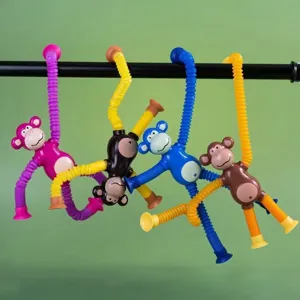 Four colorful suction cup monkey pop tube toys hanging on a black bar against a green wall.